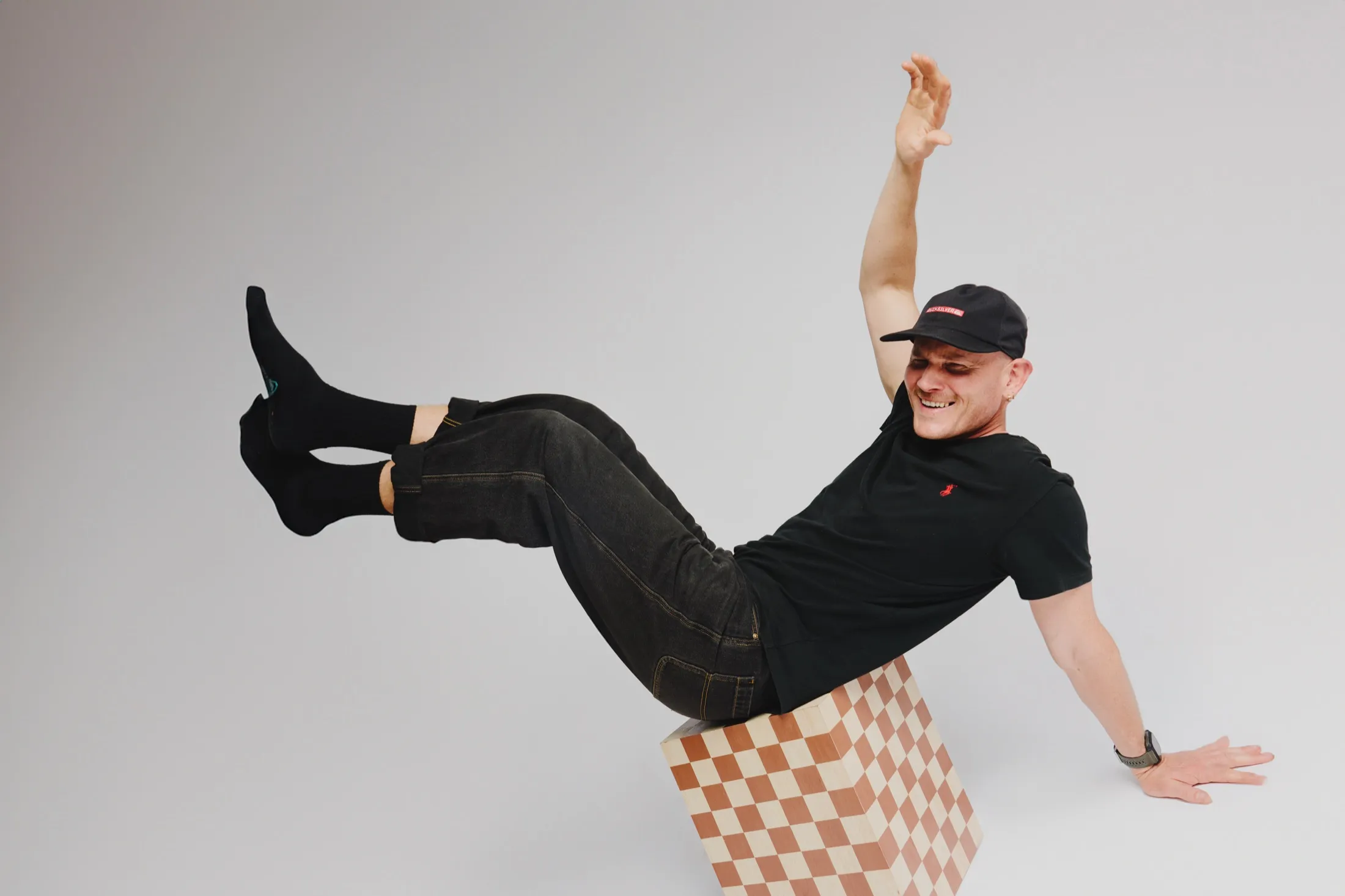Calum laughing, legs kicked up off a chequered stool